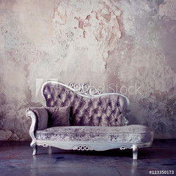 Grunge Styled Interior. Beautiful sofa in classical style on a background of textured walls. Purple toning