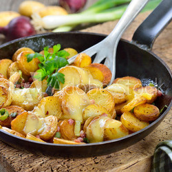 Rustikaler Snack: Ungeschälte Mini-Bratkartoffeln mit Speck und Frühlingszwiebeln überbacken mit reifem Bergkäse