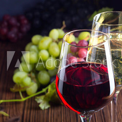 Gläser mit Rot- und Weißwein mit Trauben auf Holzuntergrund