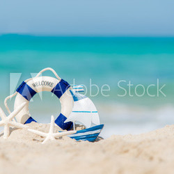 Lifebuoy on sand beach background with starfish and fishing boat, copy space.  Summer Concept