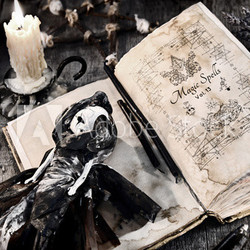 Old book with evil spells, scary doll, rune and burning candle on planks. Halloween, occult, esoteric and wicca concept. Vintage background