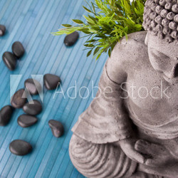 Buddha mit Bambus, Massage Steinen und Schale mit Blüten