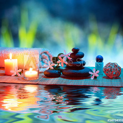 two candles and towels black stones and tiare on water