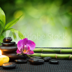 purple orchid, candle, with stones , bamboo on black mat