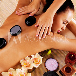 Adult woman having hot stone massage in spa salon