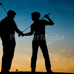 mature couple playing golf in sunset