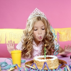 happy little blond girl blowing cake candle in a birthday party